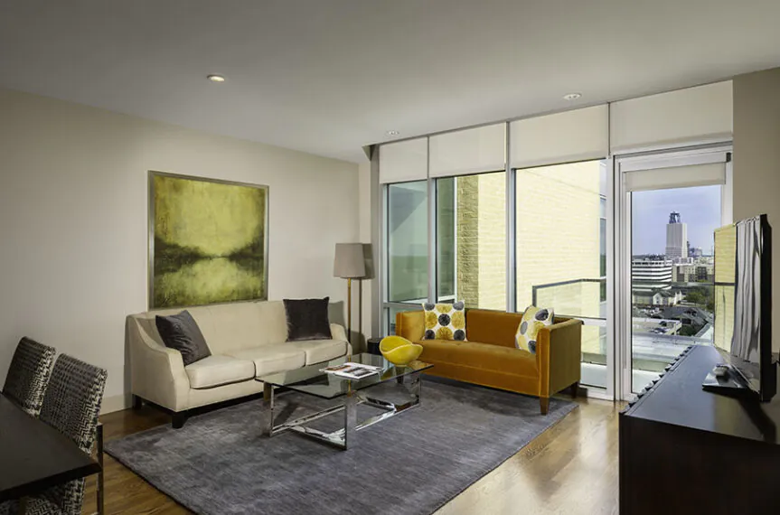Living room with white and orange sofas and large windows.
