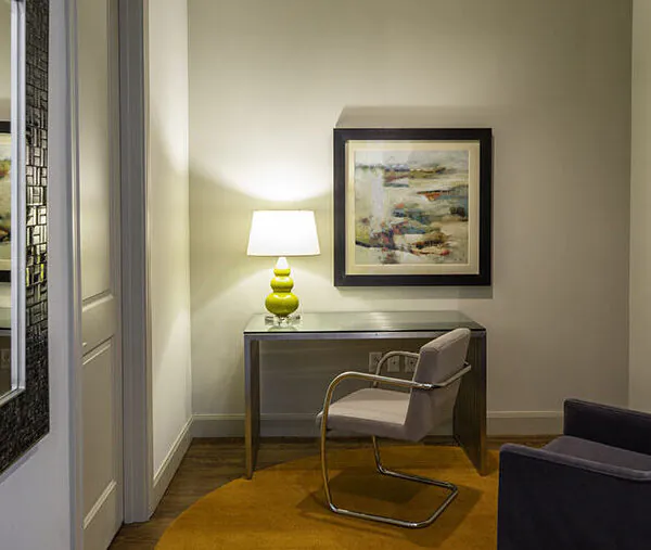 Corner with a chair, lamp and artwork on the wall.