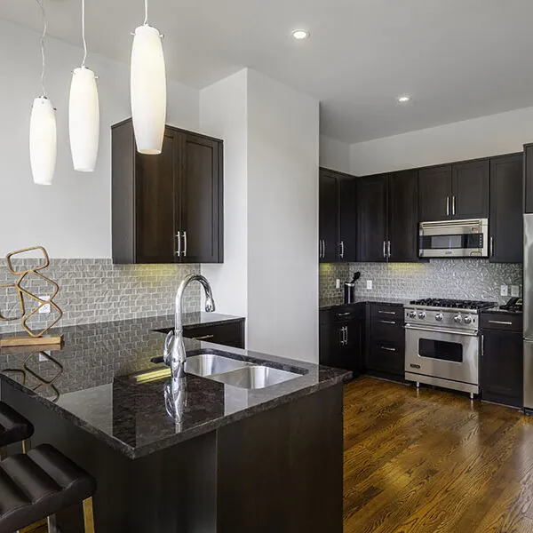 Kitchen with seating, dark cabinets and lights.