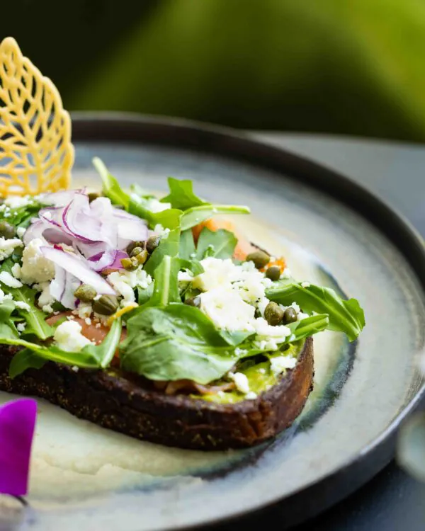 Avocado toast with greens and glass of white wine.