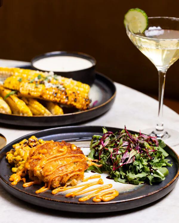 Plates of food with salad, fries, and cocktails on a table.